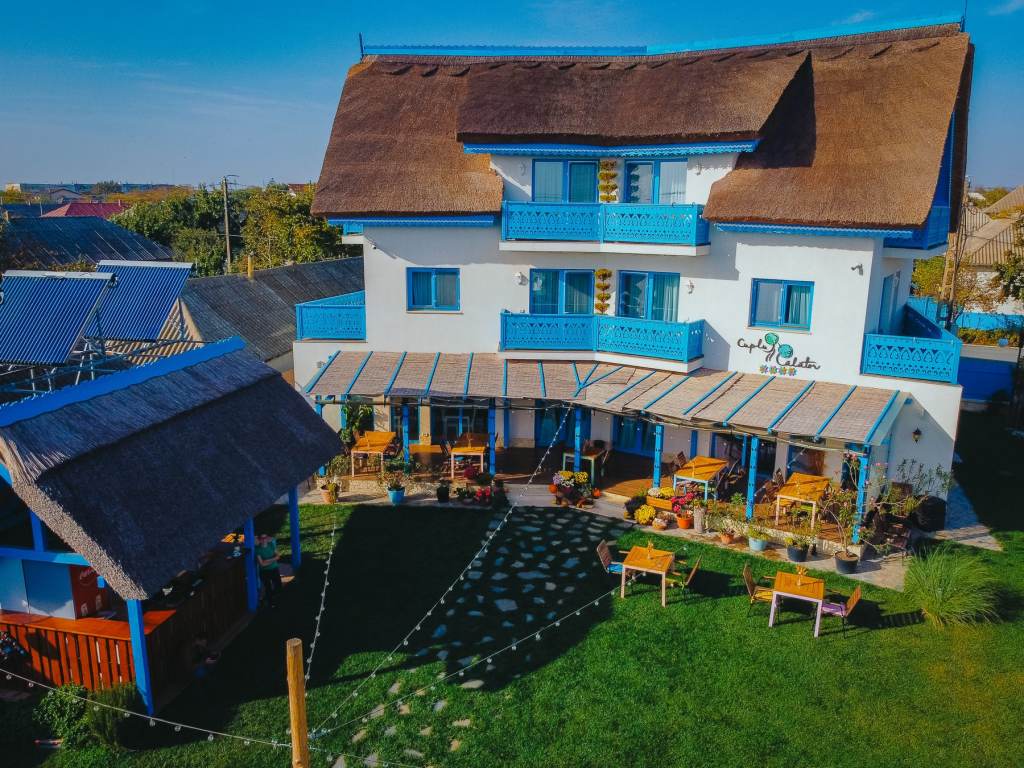 Pensiunea Cuplu Călător in Jurilovca, with its reed roof and blue balconies